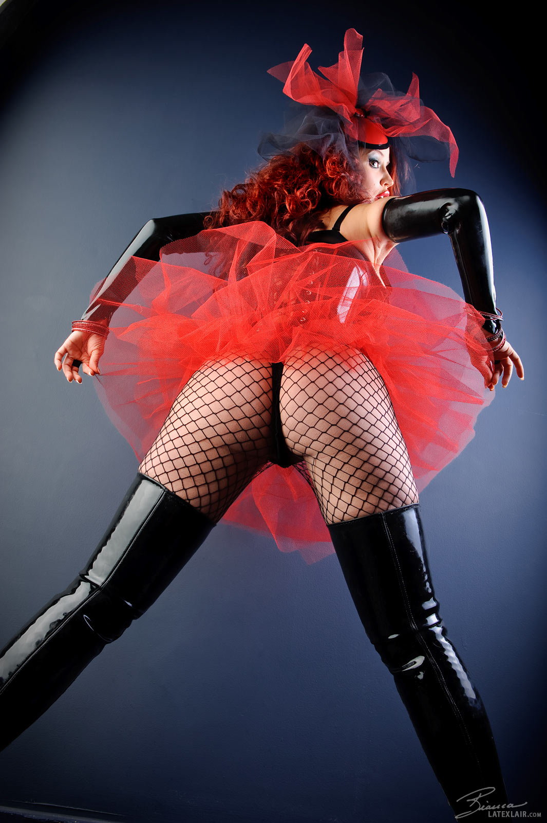 ass bianca_beauchamp boots breasts cleavage corset erect_nipples female fishnets large_breasts latex lipstick long_hair looking_back nipples red_hair simple_background skirt solo topless watermark
