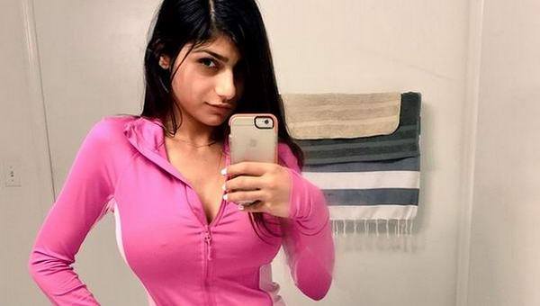 1girl breasts brown_eyes brown_hair clothed female female_only lebanese_american looking_at_viewer mia_khalifa nail_polish non-nude porn_star selfie solo tan_skin text upper_body watermark