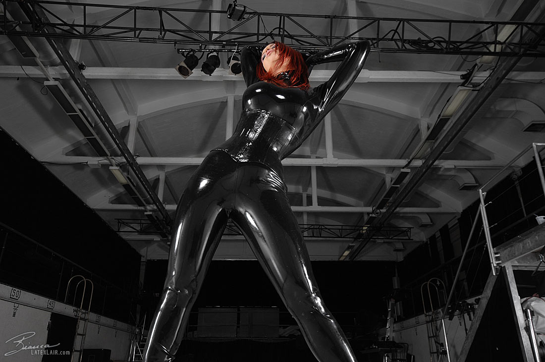 bianca_beauchamp breasts catsuit female gloves high_heels large_breasts latex long_hair red_hair shoes solo watermark