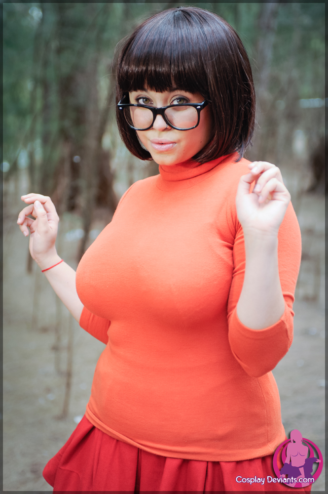 1girl breasts brown_hair clothed cosplay cosplaydeviants female female_only glasses large_breasts looking_at_viewer non-nude outside pursed_lips scooby-doo solo velma_dinkley watermark white