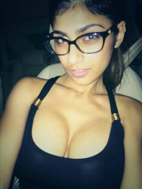 breasts brown_eyes brown_hair car cleavage female glasses lebanese_american mia_khalifa sitting solo tan_skin upper_body
