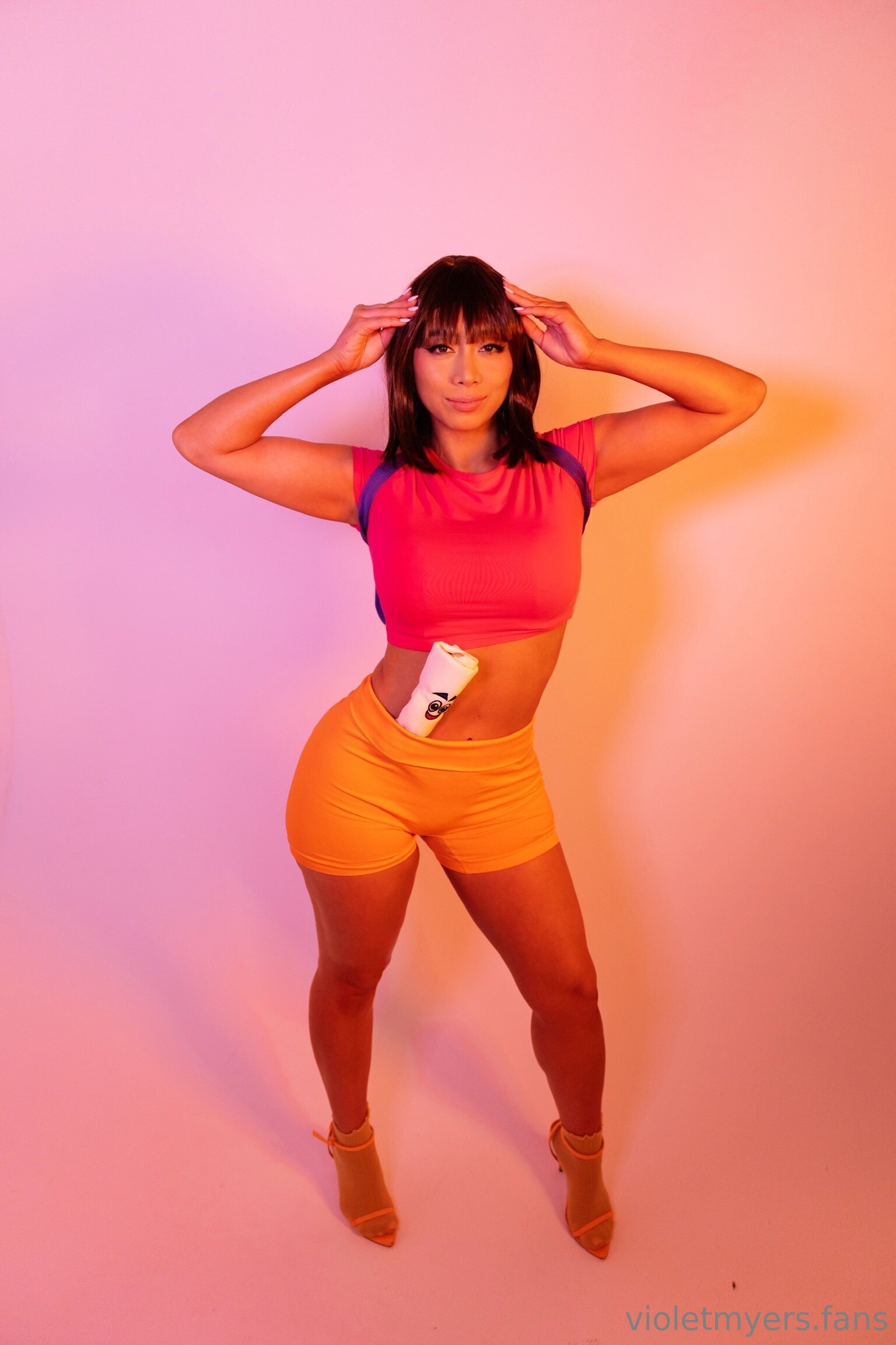 1girl arms_up backpack clothed cosplay dark_hair dora_marquez dora_the_explorer fansly female female_only high_heels looking_at_viewer midriff milf non-nude pornstar short_shorts simple_background socks solo tan_skin tight_fit violet_myers watermark