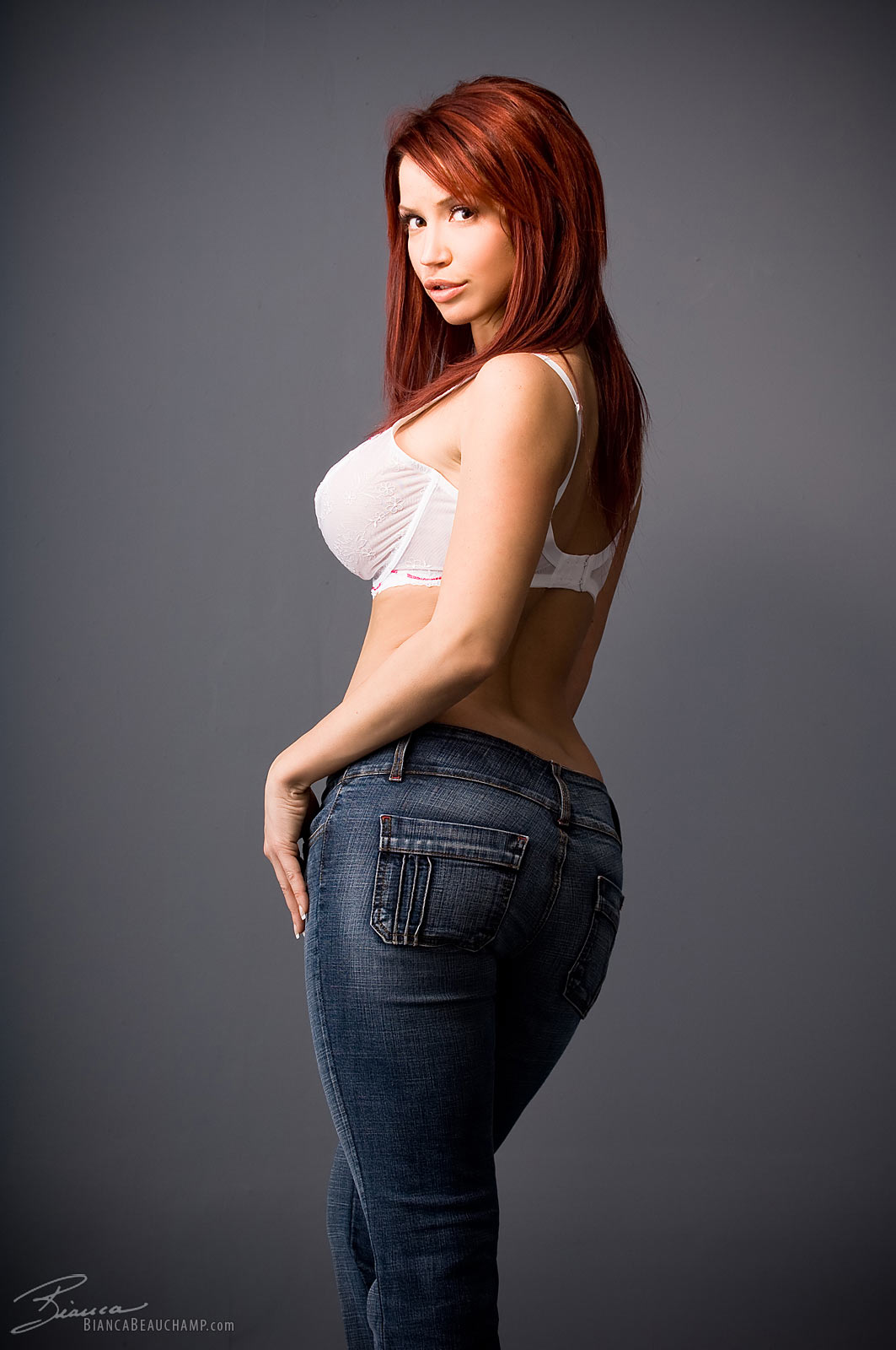 ass bianca_beauchamp breasts female jeans large_breasts long_hair looking_back red_hair simple_background solo watermark
