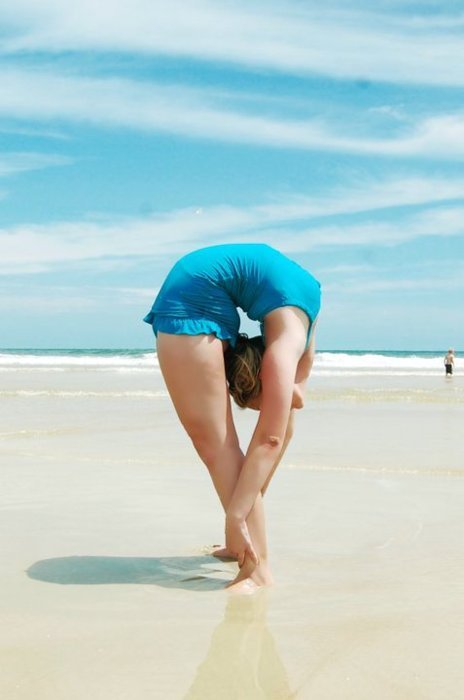 1girl beach bent_over_backwards blonde_hair blue_swimsuit contortion flexible one-piece_swimsuit solo swimsuit