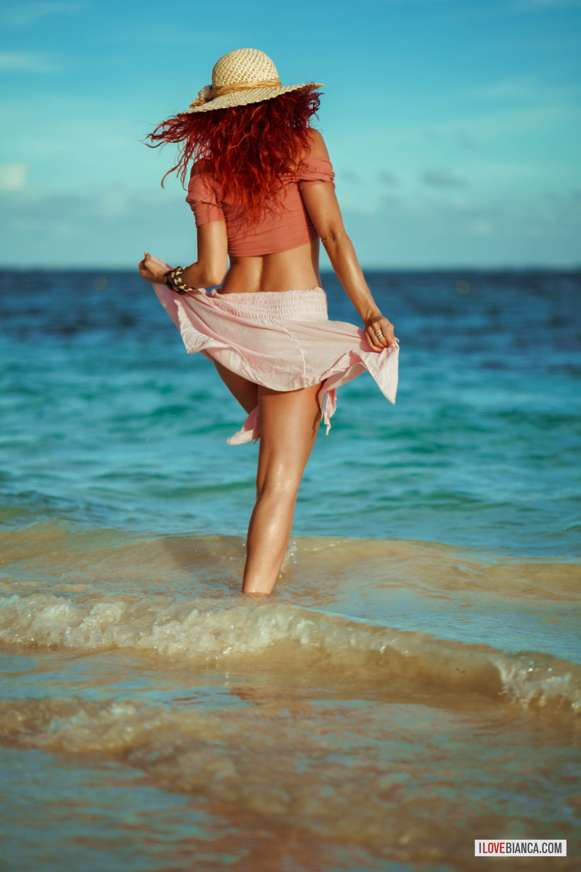 ass beach bianca_beauchamp breasts female hat large_breasts long_hair looking_back navel navel_piercing outside piercing red_hair solo water watermark