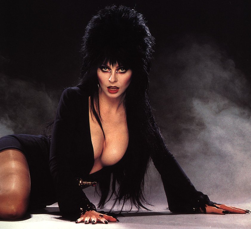 1girl big_breasts black_hair breasts cassandra_peterson celebrity cleavage dagger dress elvira elvira:_mistress_of_the_dark female female_only human large_breasts lipstick long_hair looking_at_viewer makeup open_clothes photo real_person red_lips red_lipstick uncensored