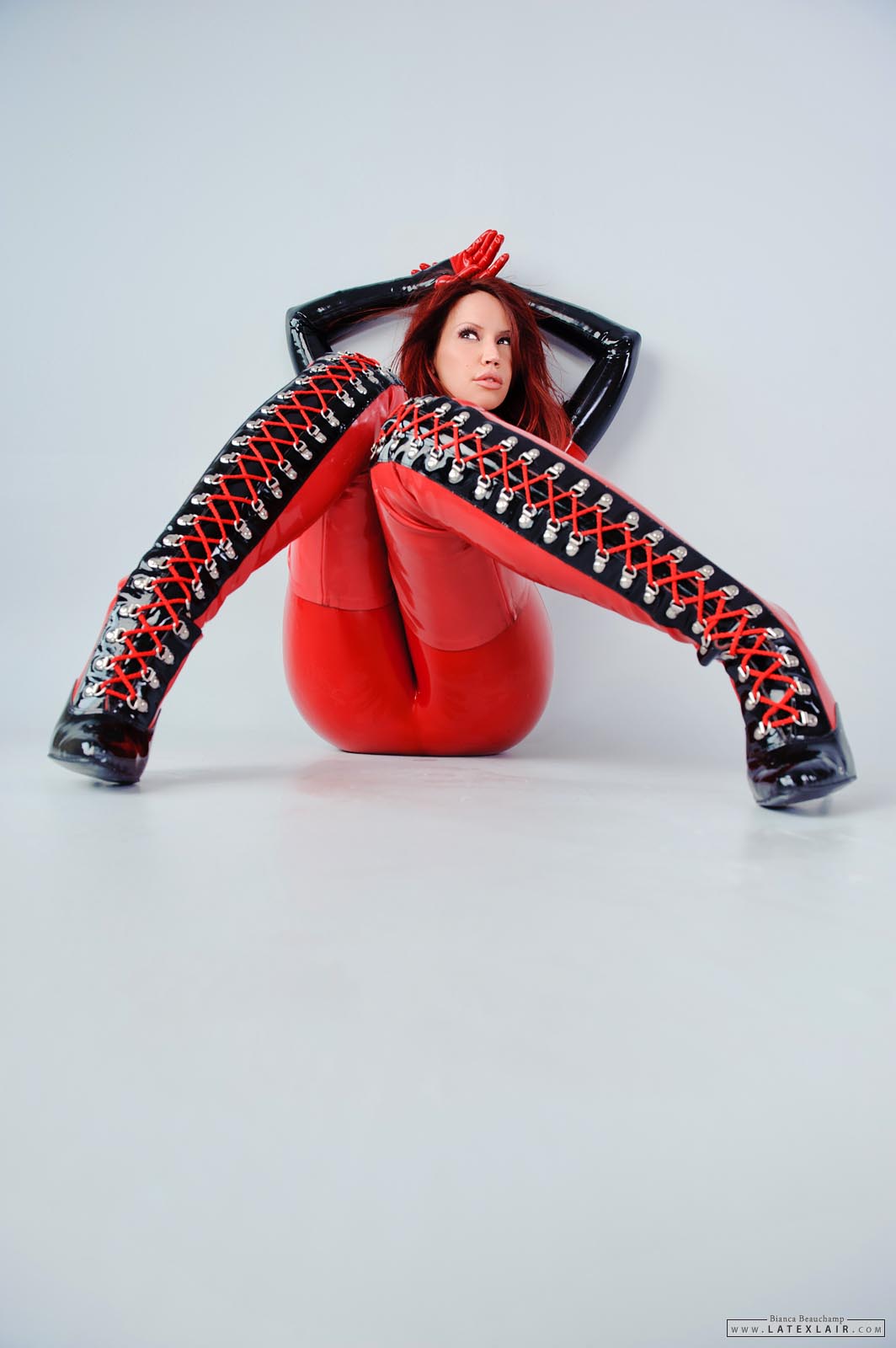 bianca_beauchamp boots breasts catsuit corset female high_heels large_breasts latex long_hair red_hair solo watermark
