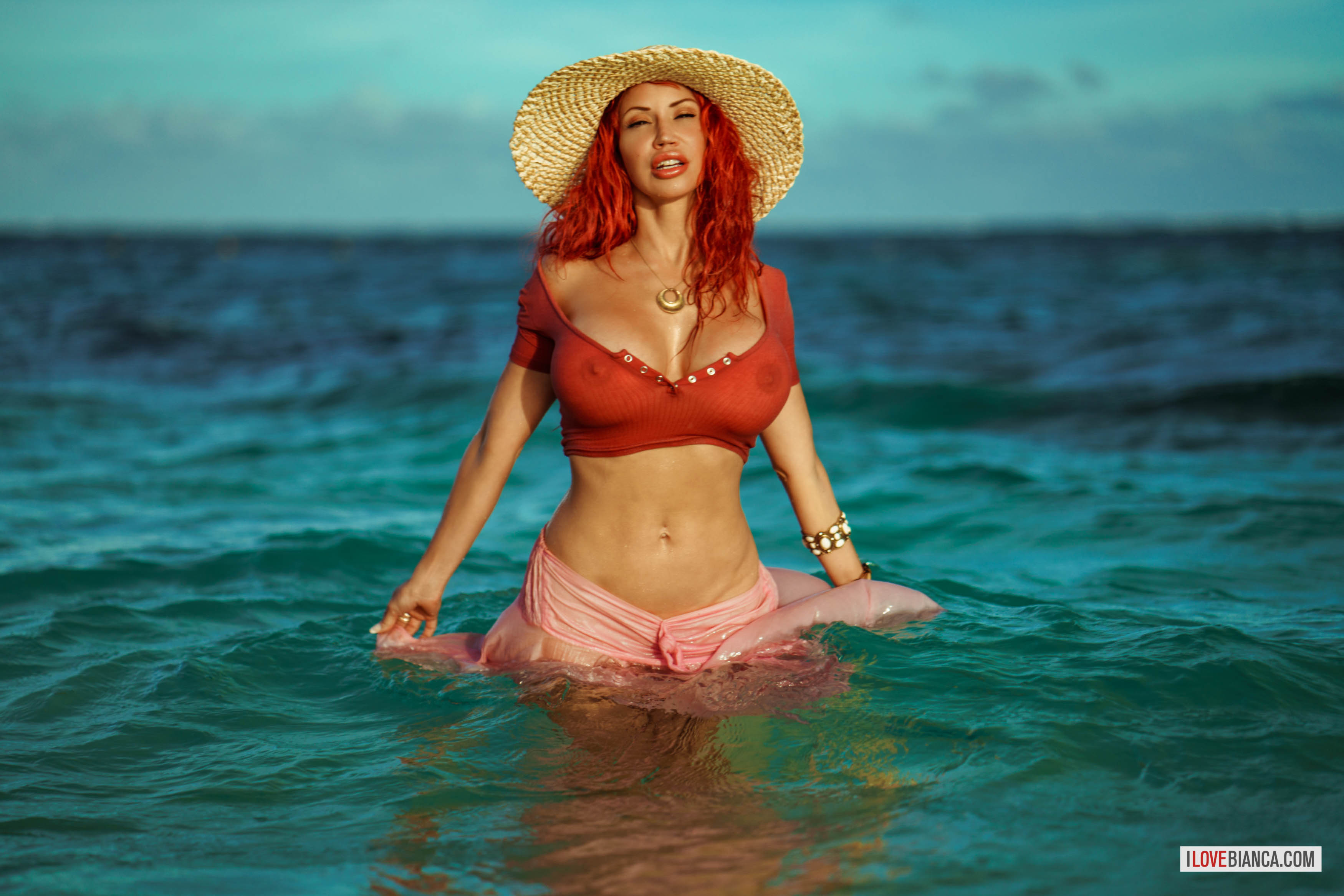 beach bianca_beauchamp breasts female hat large_breasts long_hair navel navel_piercing outside piercing red_hair solo water watermark