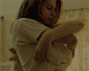 1girl alexandra_daddario animated breasts exposed_breasts female female_only gif indoors medium_breasts parted_lips shirt solo solo_female topless undressing white_shirt