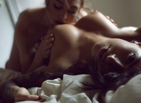 2girls arm arm_up arms babe bare_shoulders bed breast_grab breast_sucking breasts closed_eyes female girl_on_top indoors inside lesbian lips looking_at_viewer lying multiple_girls nipples nude on_back open_mouth photo tattoo