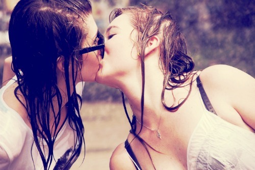 2girls bare_shoulders black_hair bra brown_hair brunette camisole closed_eyes female female_only jewelry kissing lesbian long_hair multiple_girls neck necklace outside photo real_person see-through shirt sunglasses t-shirt upper_body wet wet_clothes wet_hair