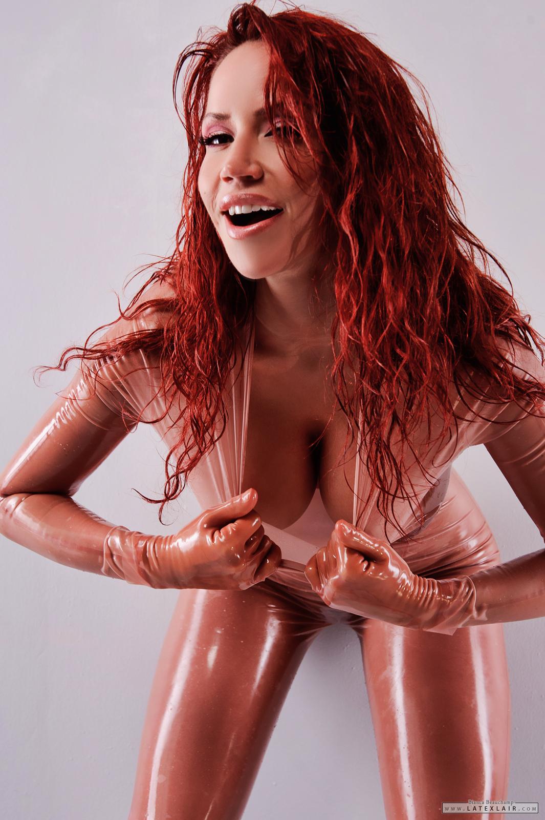 bianca_beauchamp breasts catsuit erect_nipples female gloves large_breasts latex long_hair navel navel_piercing nipples piercing red_hair see-through simple_background solo watermark