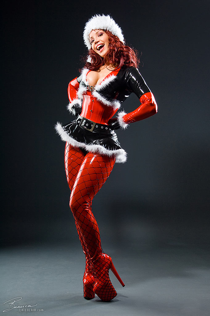 belt bianca_beauchamp breasts cleavage corset female fishnets hat high_heels large_breasts latex long_hair red_hair santa_hat shoes simple_background skirt solo