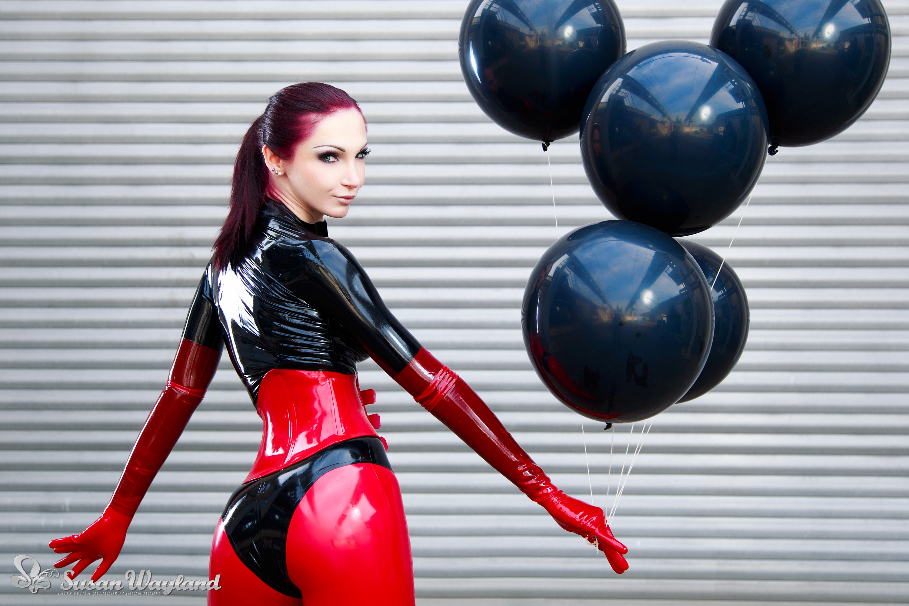 ass balloon black_hair breasts catsuit corset female gloves high_heels large_breasts latex long_hair looking_back shoes solo susan_wayland watermark