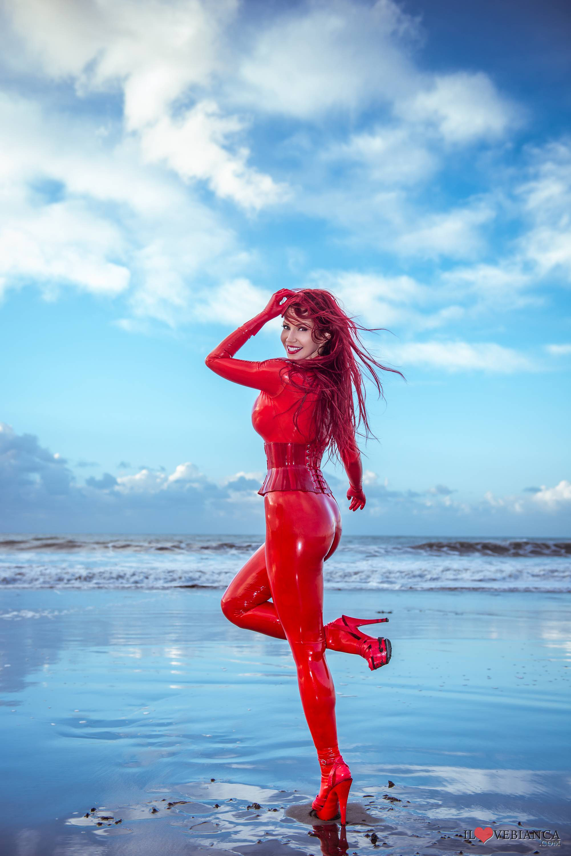 ass beach bianca_beauchamp breasts catsuit female gloves large_breasts latex long_hair looking_back outside red_hair solo water watermark