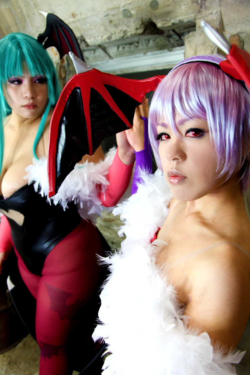 2girls aqua_hair bare_shoulders breasts chouzuki_maryou cleavage cosplay darkstalkers female female_only huge_breasts leotard lilith_aensland long_hair looking_at_viewer morrigan_aensland non-nude pantyhose partially_clothed plump purple_hair solo succubus suzuka_itsuki thong_leotard watermark wings