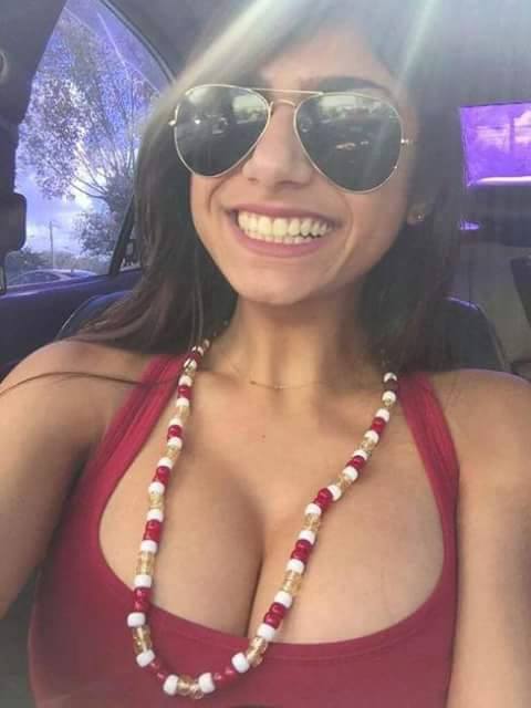 breasts brown_eyes brown_hair car cleavage female glasses lebanese_american mia_khalifa necklace smile tan_skin