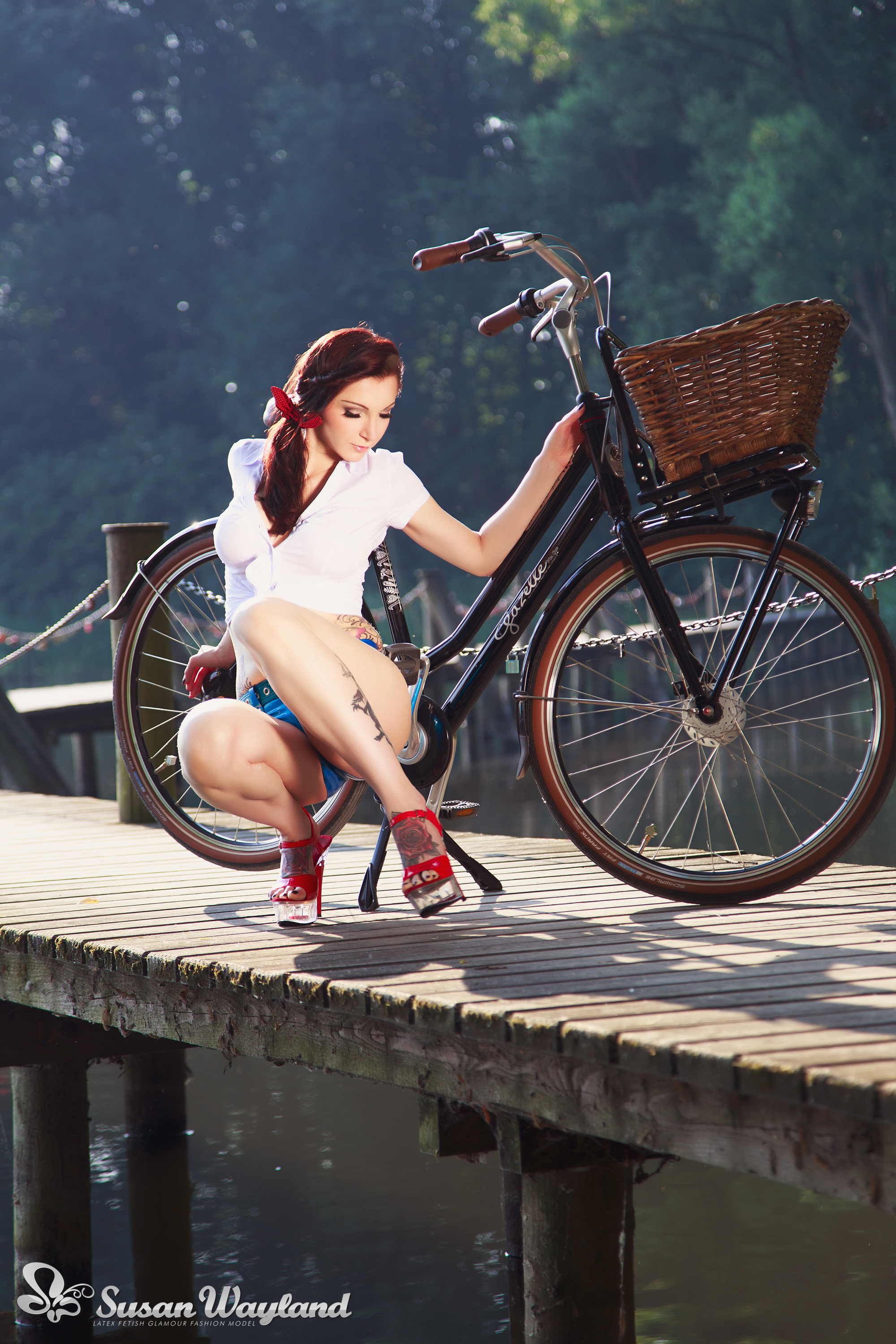 bicycle black_hair breasts female forest high_heels hotpants large_breasts latex long_hair midriff navel navel_piercing outside piercing ponytail shoes short_shorts solo susan_wayland tattoo watermark
