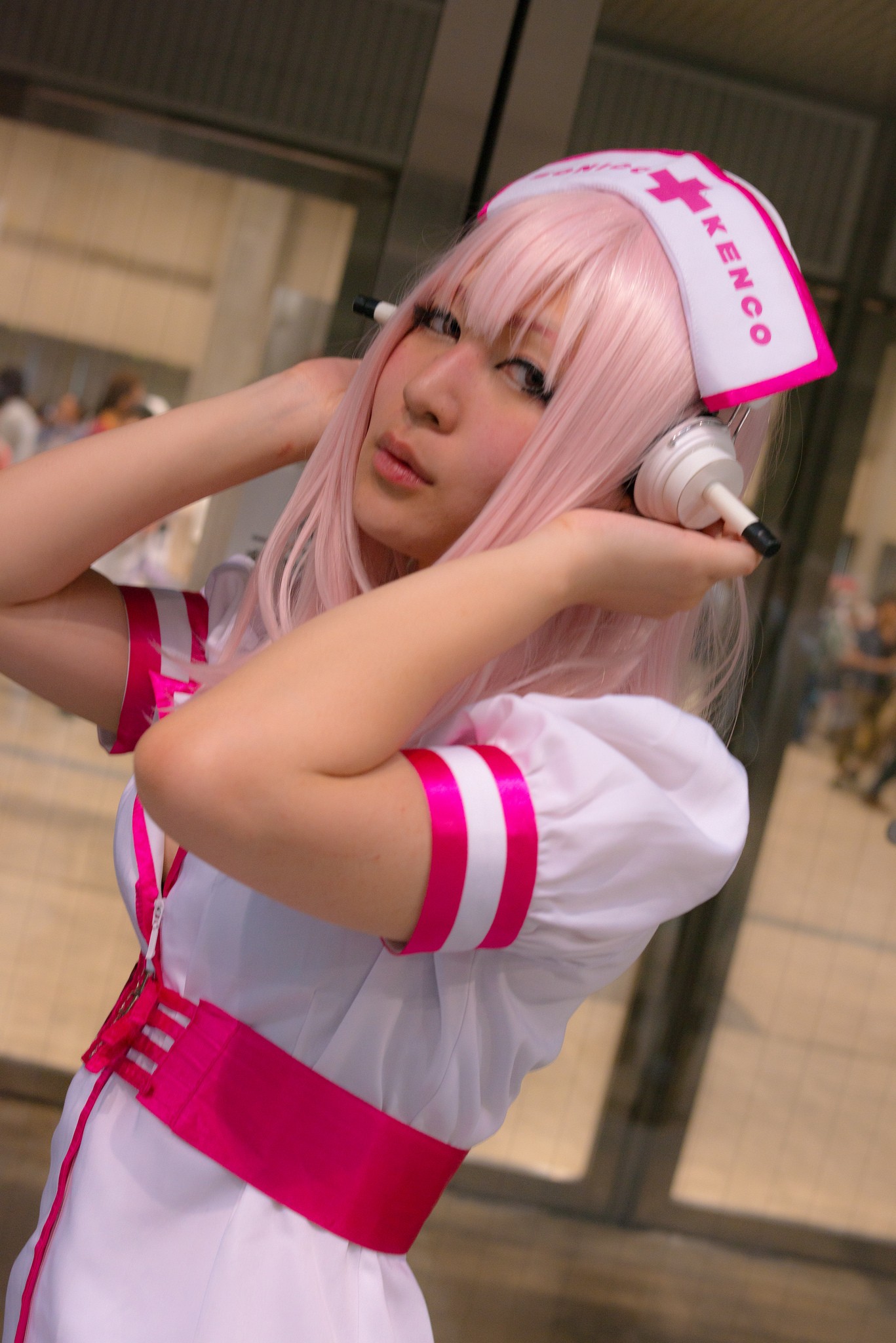 1girl asian breasts cosplay dress female headphones japanese long_hair nurse pink_hair solo super_sonico