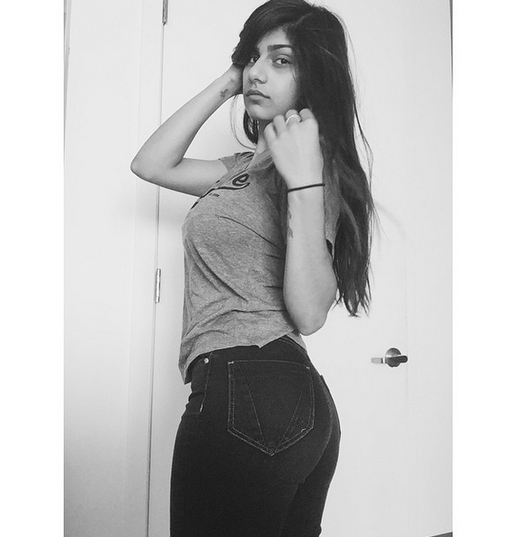 1girl ass breasts brown_eyes brown_hair clothed female female_only improveme jeans lebanese_american looking_at_viewer mia_khalifa monochrome non-nude porn_star tan_skin text watermark