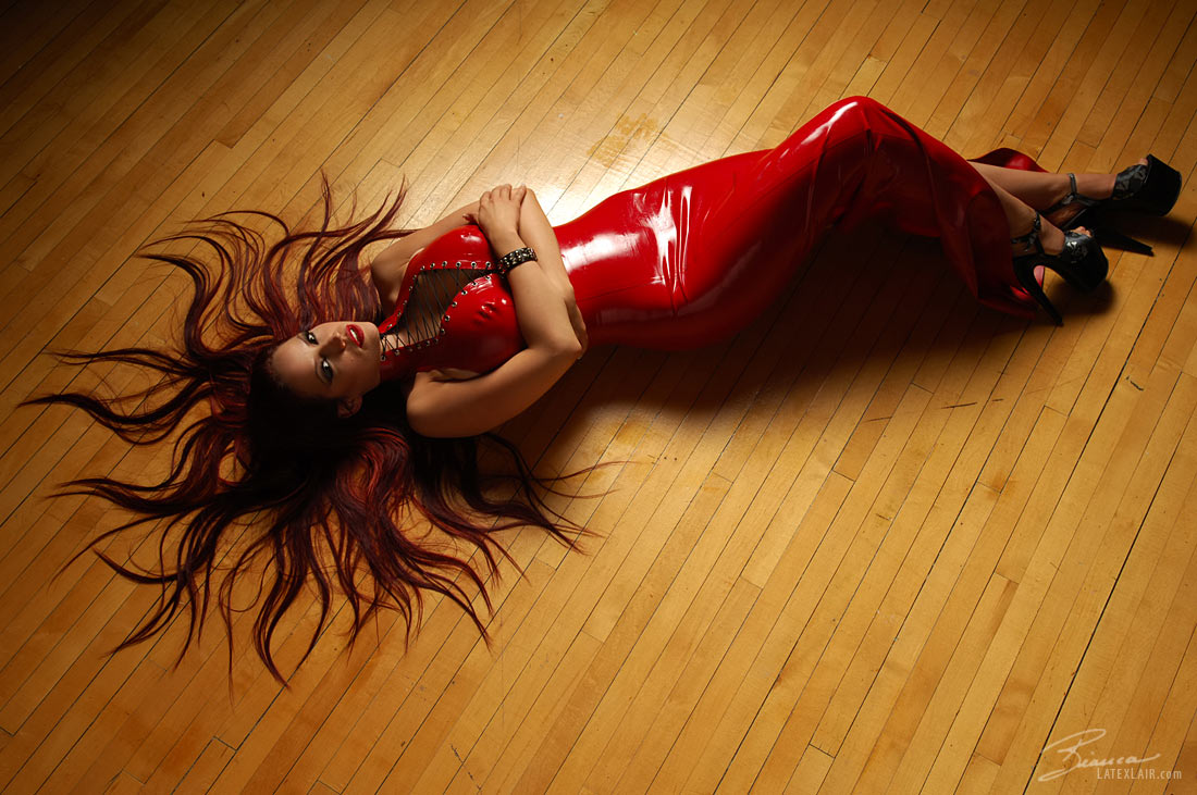 bianca_beauchamp breasts cleavage dress female high_heels large_breasts latex lipstick long_hair lying red_hair shoes solo watermark