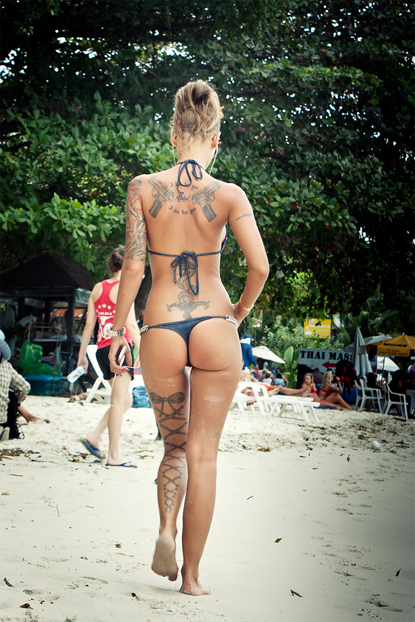 ass backside beach bikini blonde_hair hair_up halterneck outside sandy slender swimsuit tattoo thong