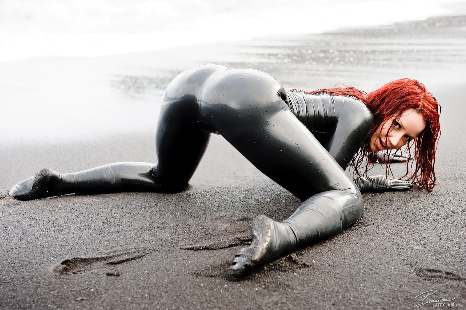 ass beach bianca_beauchamp breasts catsuit female gloves high_heels large_breasts latex long_hair looking_back outside red_hair sand shoes solo water watermark wet