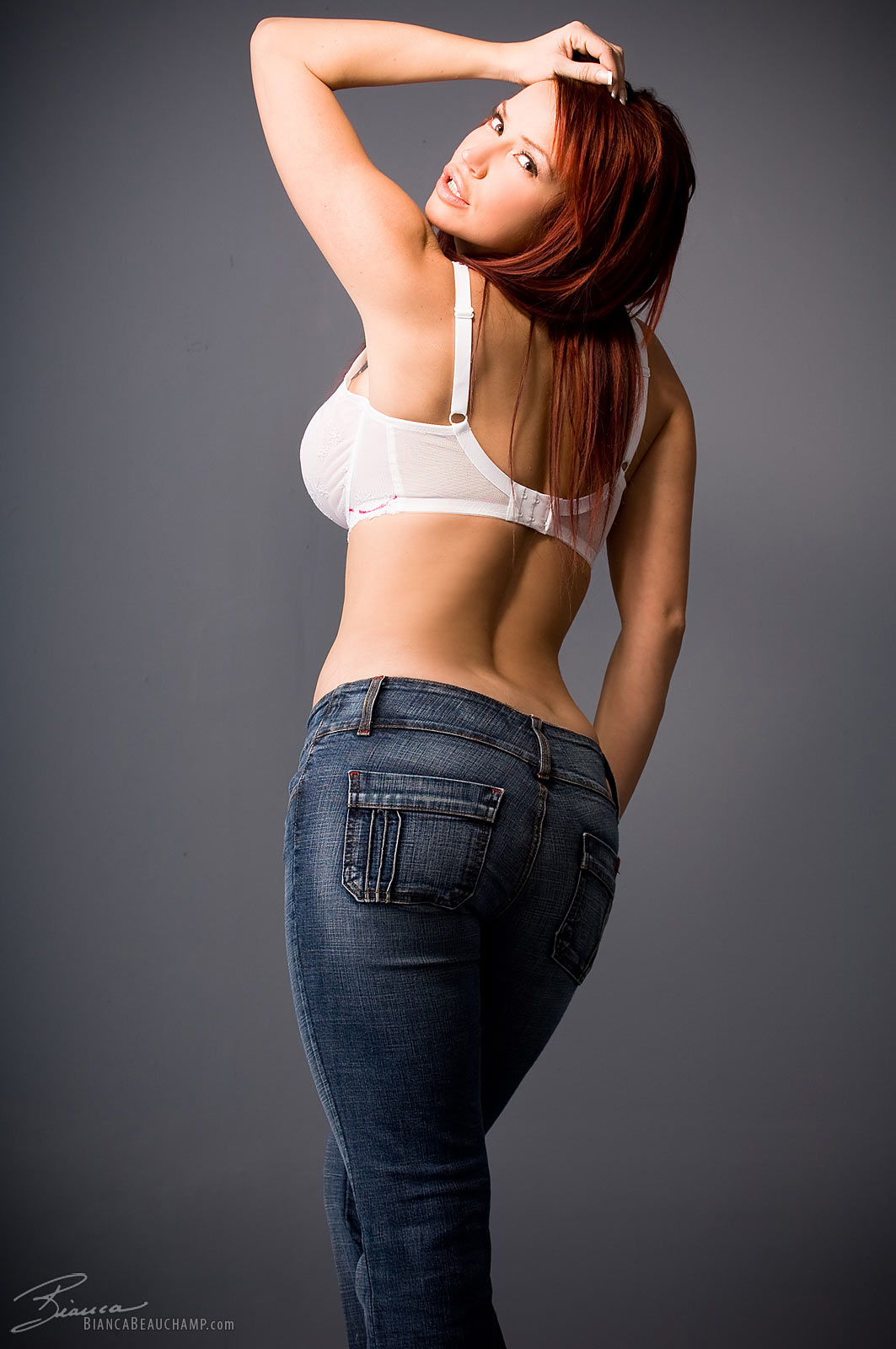 ass bianca_beauchamp breasts denim female jeans large_breasts long_hair looking_back red_hair solo watermark white_bra