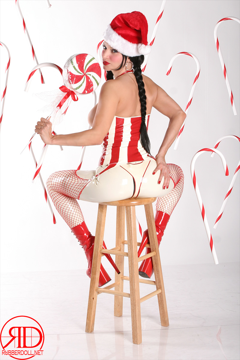 black_hair breasts candy_cane christmas female fishnets garter_belt hat high_heels large_breasts latex long_hair pasties rubberdoll santa_hat shoes simple_background solo thighhighs watermark