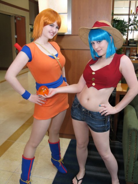 2girls blue_hair bulma_briefs cosplay dragon_ball dragon_ball_z female female_only furniture indoors jean_shorts monkey_d._luffy nami navel no_bra non_nude one_piece orange_hair orange_shirt photo plants real real_person red_shirt rule_63 son_goku under_30