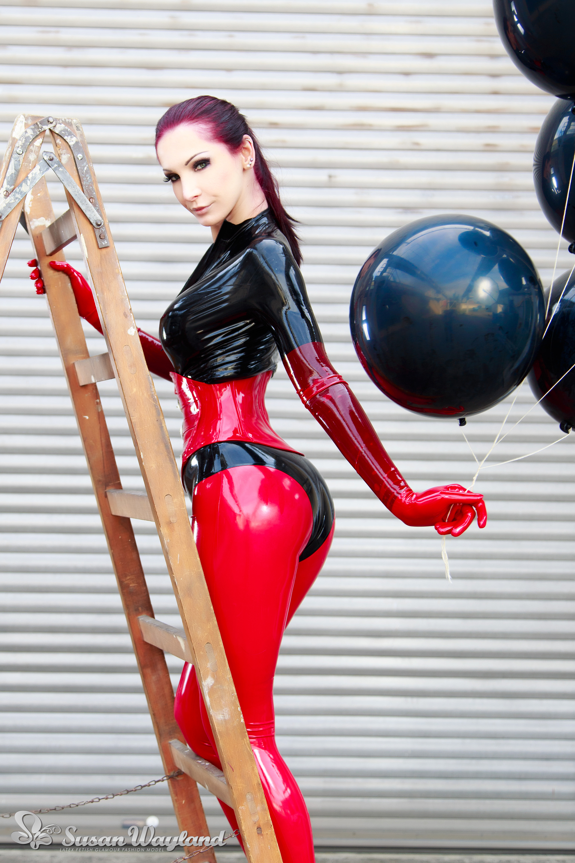 ass balloon black_hair breasts catsuit corset female gloves high_heels ladder large_breasts latex long_hair looking_back shoes solo susan_wayland watermark