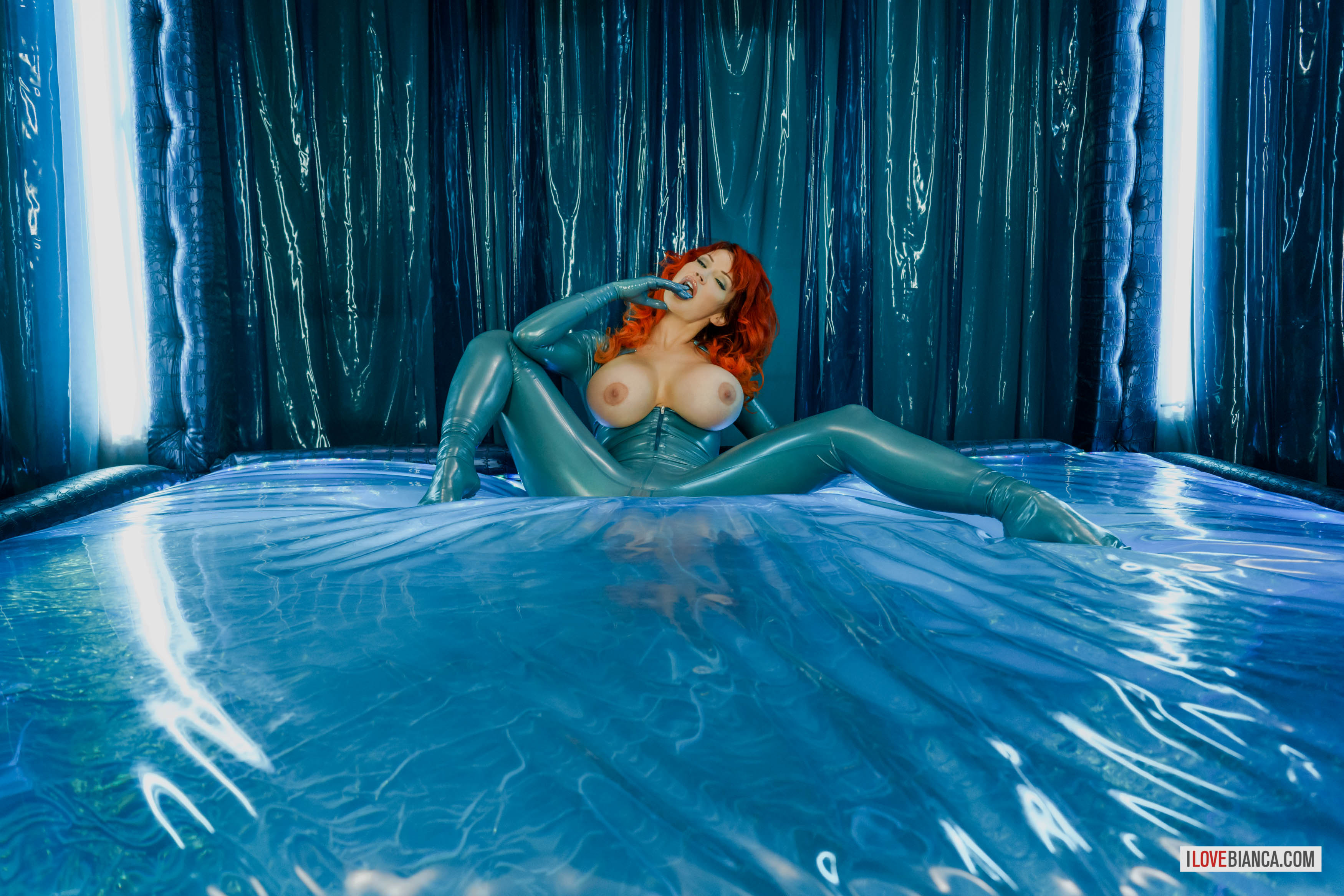 bed bianca_beauchamp breasts catsuit female high_heels large_breasts latex long_hair red_hair shoes solo watermark