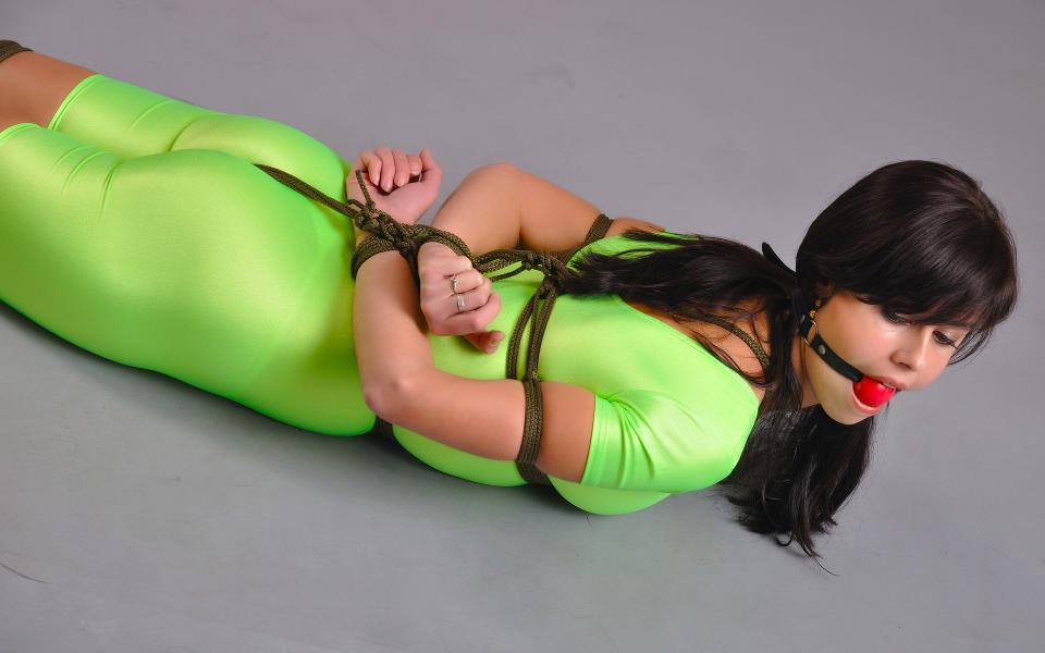 arms_behind_back ball_gag black_hair bondage bound_arms bound_legs bound_wrists crotch_rope dark_hair female gag green non-nude photo rope_bondage solo spandex tied