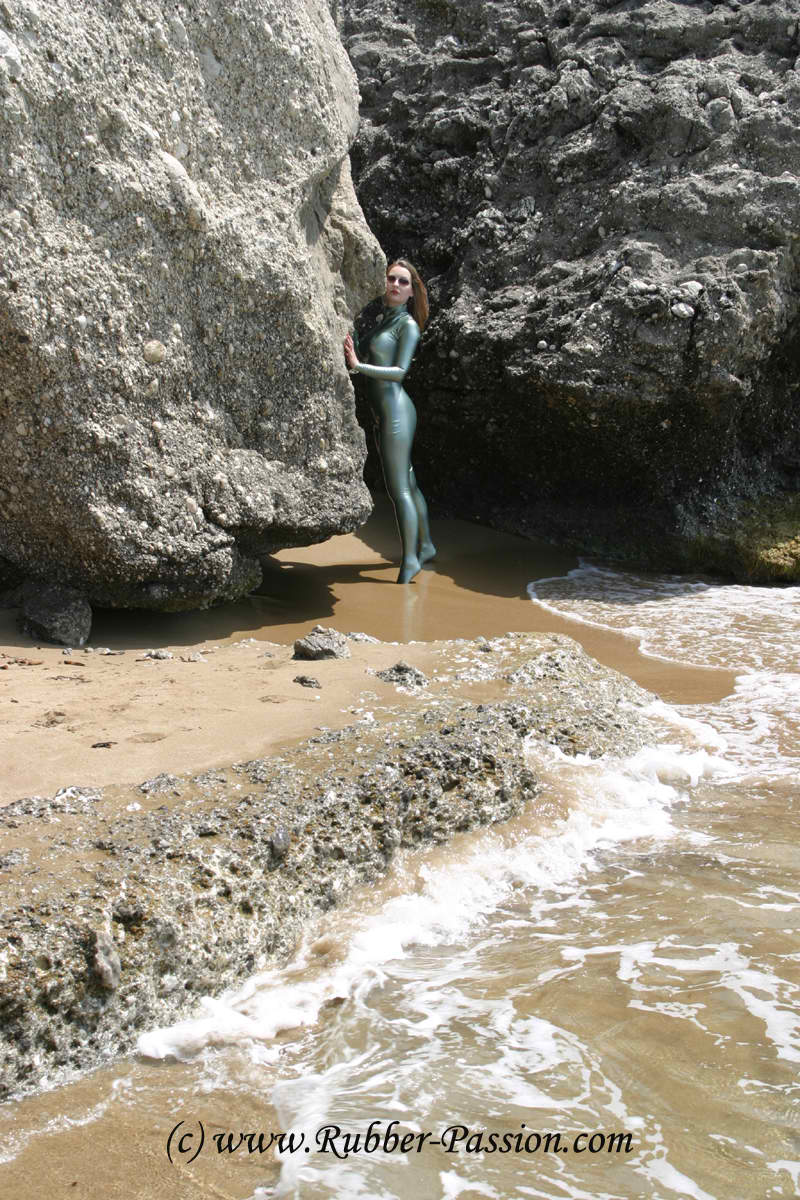 beach blonde_hair breasts catsuit female large_breasts latex long_hair outside solo sunglasses water watermark wet