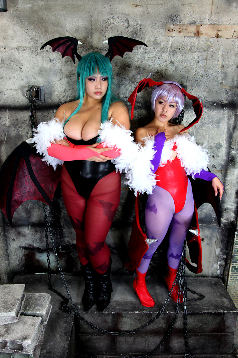2girls aqua_hair breasts capcom chouzuki_maryou cleavage cosplay darkstalkers female female_only huge_breasts lilith_aensland long_hair morrigan_aensland non-nude partially_clothed plump purple_hair solo succubus suzuka_itsuki watermark wings
