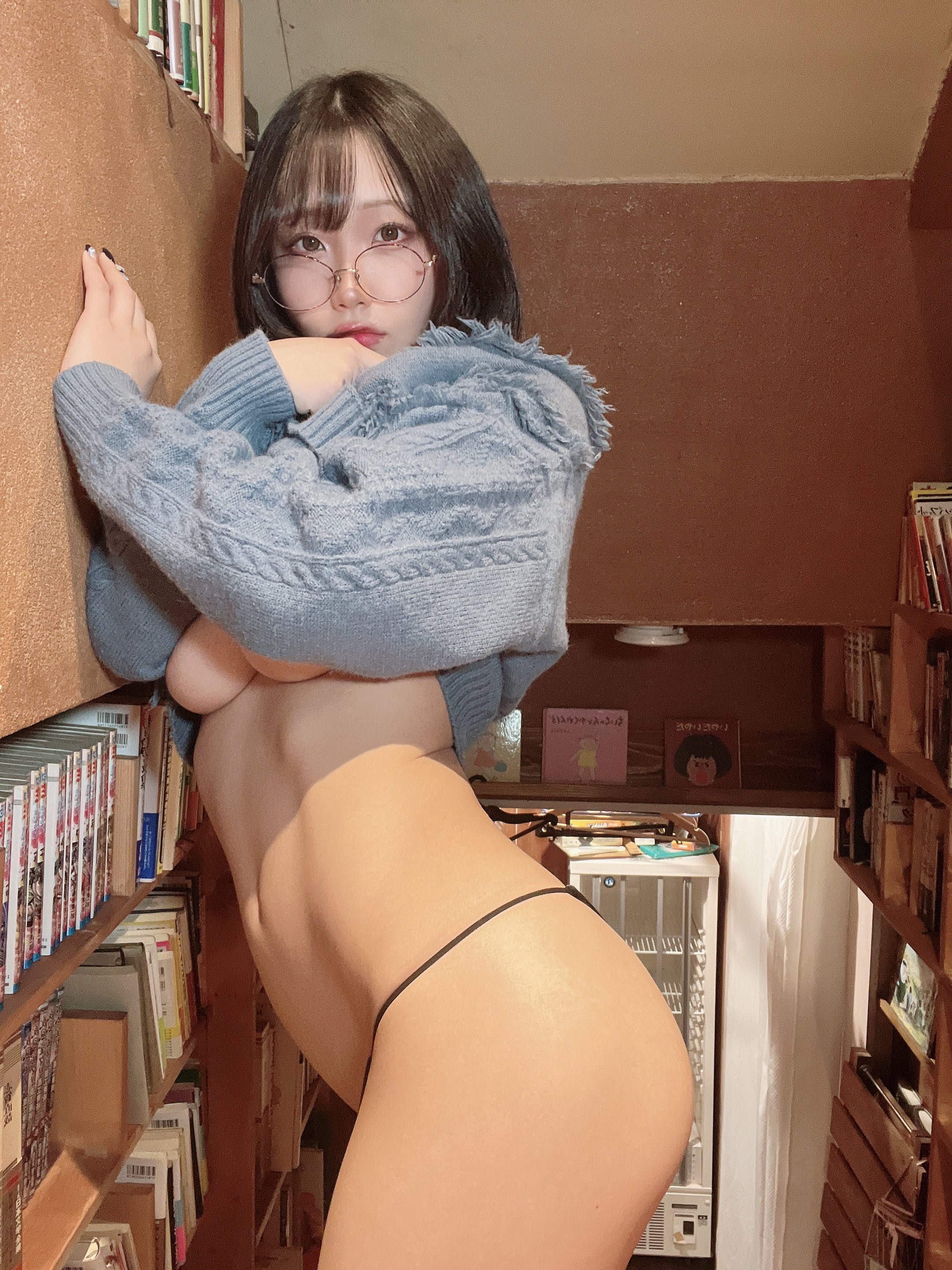 1girl against_wall asian asian_female black_hair black_panties blue_sweater book bookshelf breasts brown_eyes brown_hair clothes_lift from_side glasses hikabebe indoors japanese large_breasts lips long_sleeves looking_at viewer nail_polish navel no_bra panties round_eyewear short_hair solo sourced standing stomach sweater sweater_lift thong underboob underwear