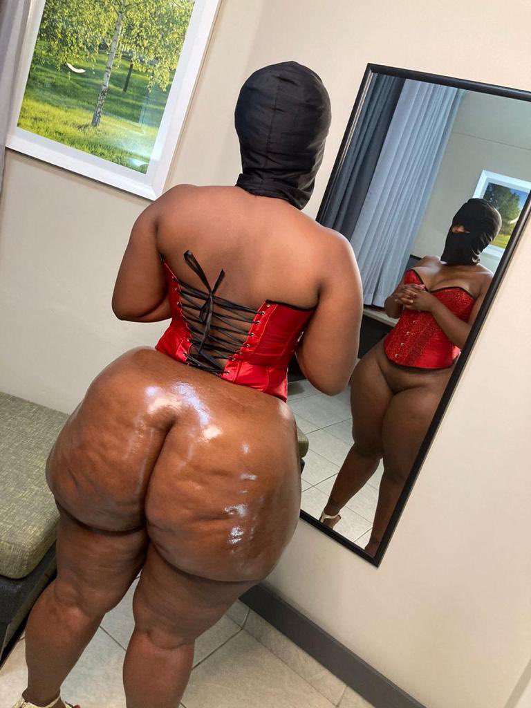 1girl ass big_ass black_hair bottomless cellulite chubby cleavage corset dark-skinned_female dark_skin ebony female female_focus female_only female_solo long_hair mask massive_ass mirror presenting_ass reflection solo standing tattoo the_real liso thick thong window