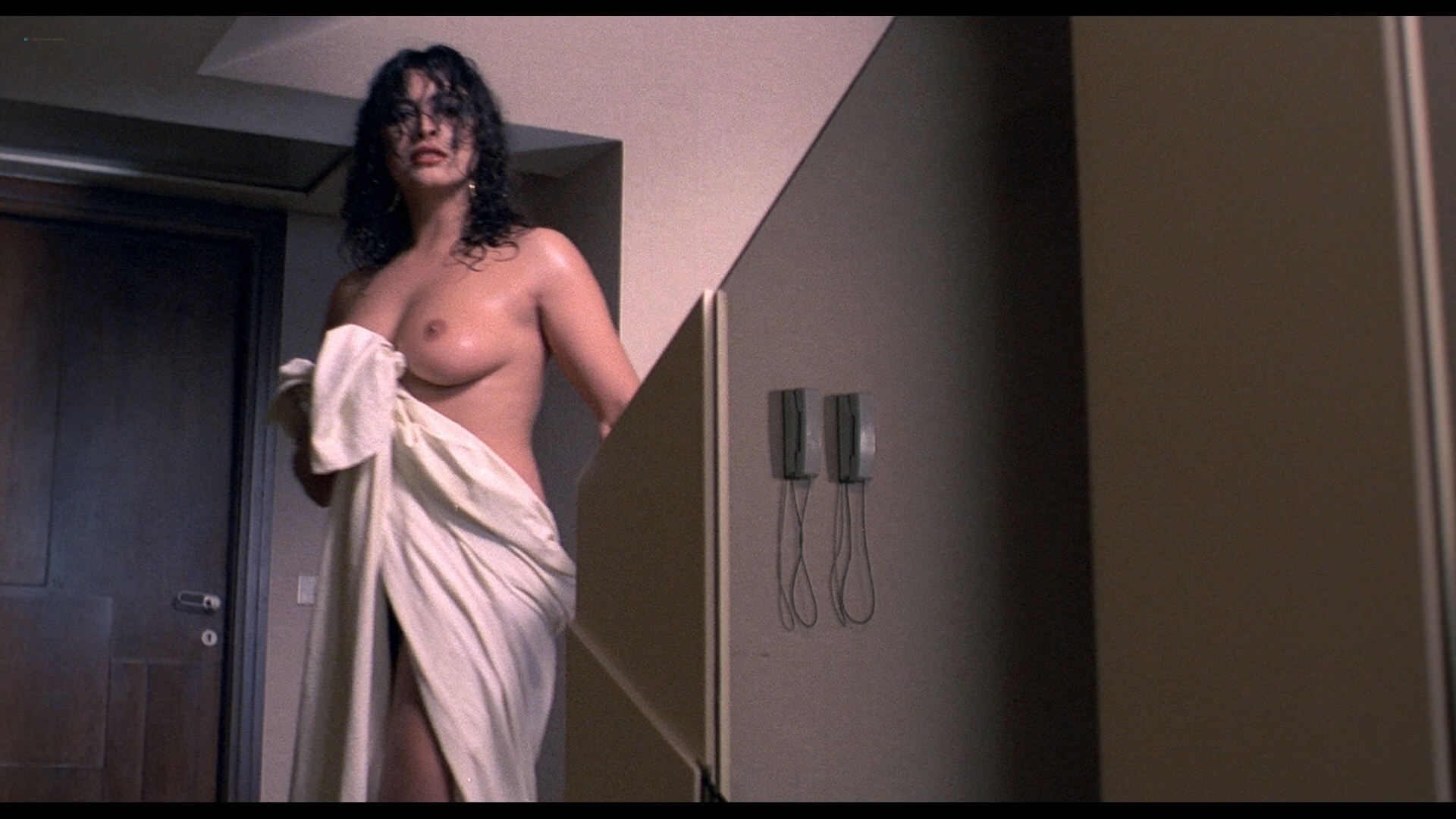 absurdres actress after_shower black_hair books bookshelf cleavage earrings emotionless emotionless_female erect_nipple expressionless highres huge_breasts huge_tits indifferent lamp long_hair marion_vainte mirella_banti phone poster record_player red_lipstick robe screenshot strutting tenebre unbothered wet_hair wine