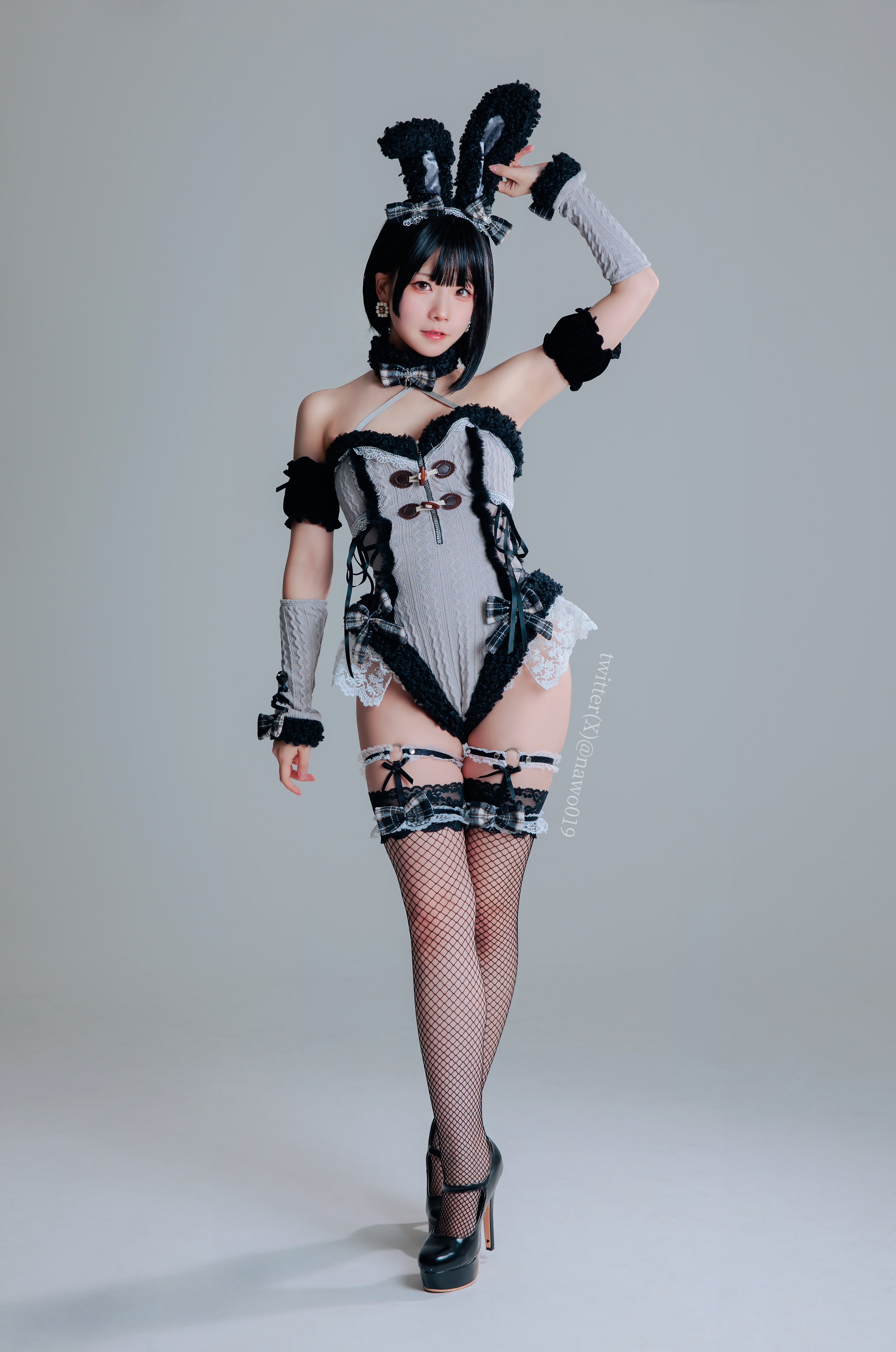 1girl animal_ears arm_raised armpits asian asian_female bare_shoulders black_footwear black_hair bow detached_sleeves earrings fake_animal ears fishnet_thighhighs fishnets full_body high_heels japanese jewelry leotard looking_at viewer playboy_bunny rabbit_ears short_hair simple_background solo sourced standing thighhighs thighs twitter_username white_background wrist_cuffs