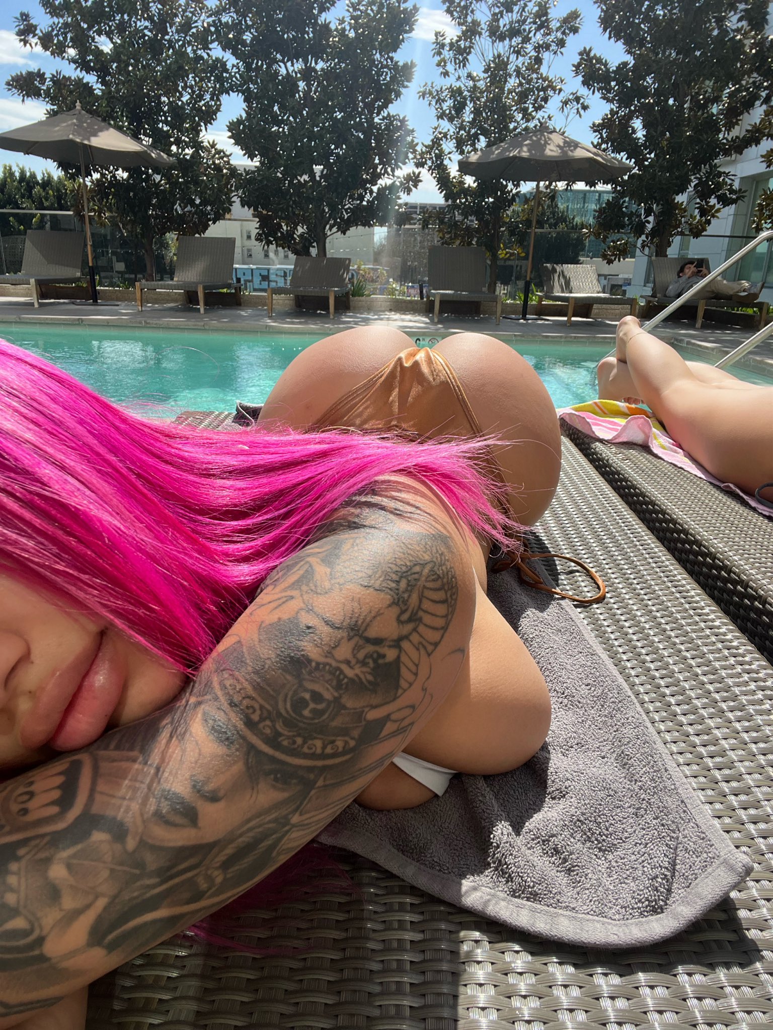 1girl ass bikini breast_press breasts ebony female female_only huge_ass huge_breasts long_hair lying pink_hair pool tattoo tattoo_on arm water