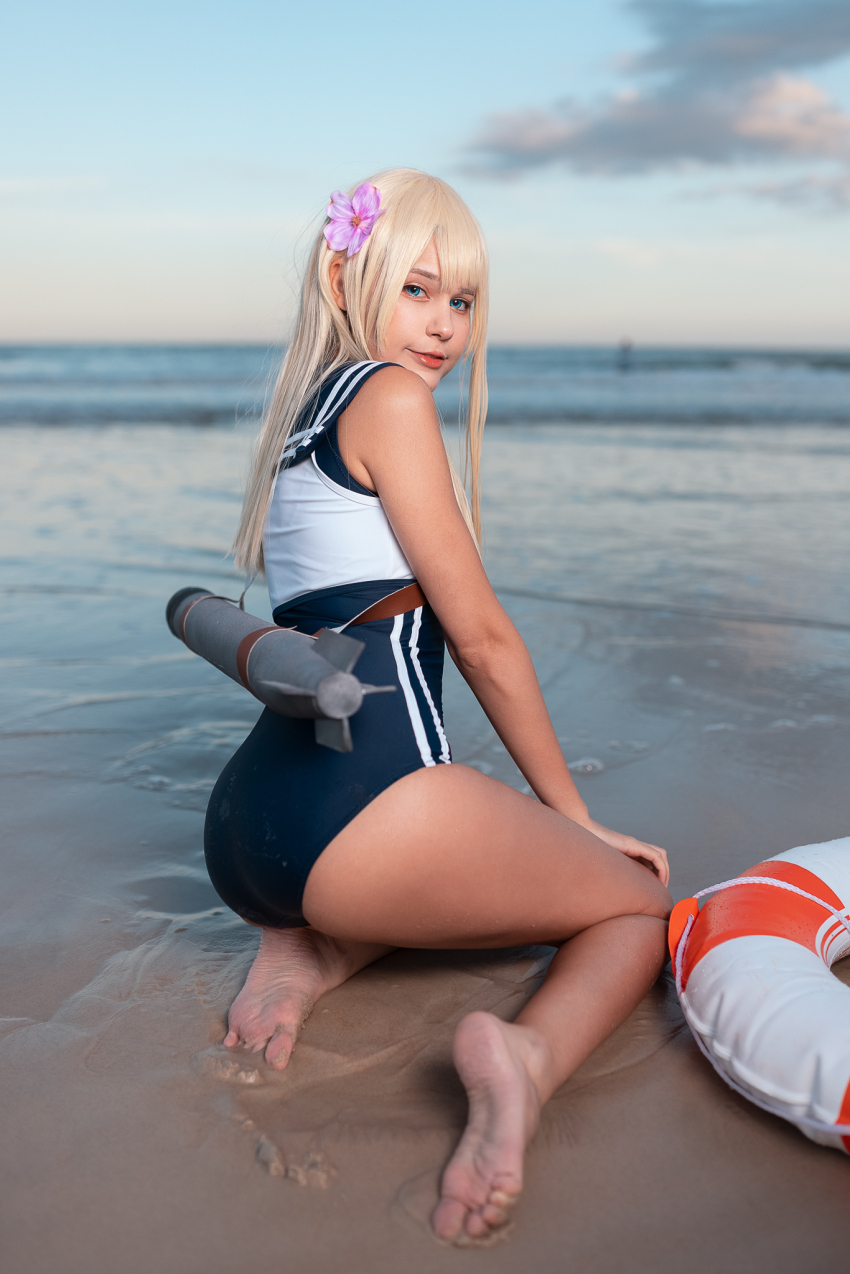 1girl ass beach blonde_hair blue_eyes cosplay cuban feet from_behind innertube jean_wanwan kantai_collection kneeling looking_at_viewer looking_back one-piece_swimsuit outside ro-500_(kantai_collection) soles solo