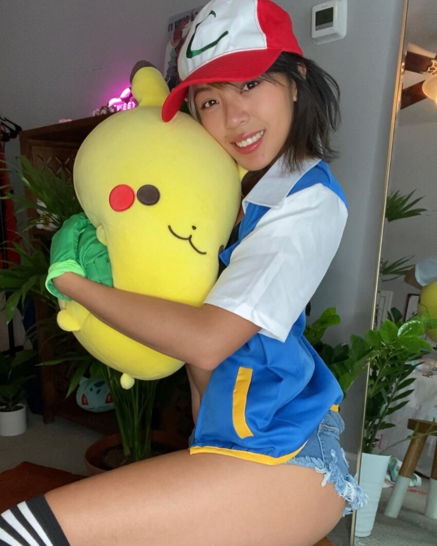 1girl ash_ketchum asian asian_female brunette cartoon chanco_cat clothed clothed_female cosplay dark_hair dark_haired_female denim_shorts female_focus female_only looking_at_the_viewer looking_at_viewer medium_hair nintendo non_nude pikachu pokemon sfw shorts solo solo_female solo_focus thigh