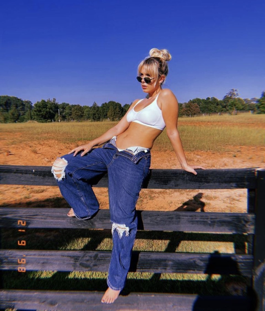 1girl bikini blonde_hair celebrity clothed feet female female_only hair_up jeans looking_away midriff millie_bobby_brown nail_polish non-nude outside parted_lips solo sunglasses