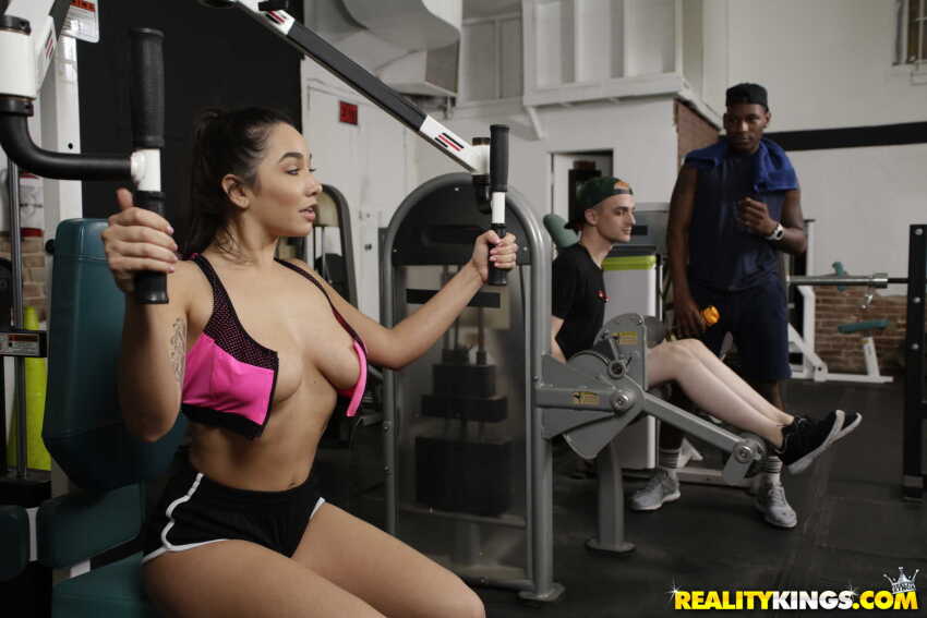 1girl 2boys being_watched breasts brunette exhibitionism female gym gym_clothes gym_equipment hetero highres jay_smooth karlee_grey light-skinned_female light-skinned_male long_hair male male/female medium_breasts natural_breasts open_shirt photo ponytail pornstar realitykings sfw sourced straight watching white_female white_male