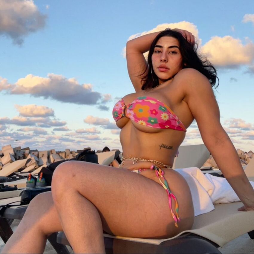 1girl arm_up bikini black_hair breasts female female_focus female_only female_solo huge_ass long_hair looking_at_viewer medium_breasts sara_pereira sitting solo solo_female solo_focus tattoo